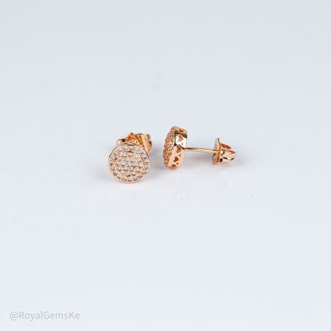A pair of rose gold stud earrings with pavé-set round-cut clear gemstones, shown on a clean white background. One earring is facing forward to show the round pavé face, while the other is turned sideways showing the post and backing.