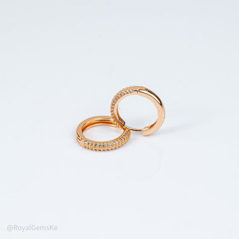 A pair of rose gold huggie hoop earrings adorned with small pavé-set clear stones, displayed on a clean white background.