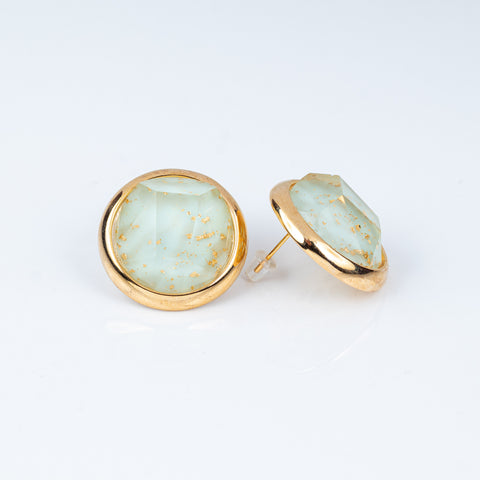 Pair of earrings with gold rims and light blue gemstones on a white background