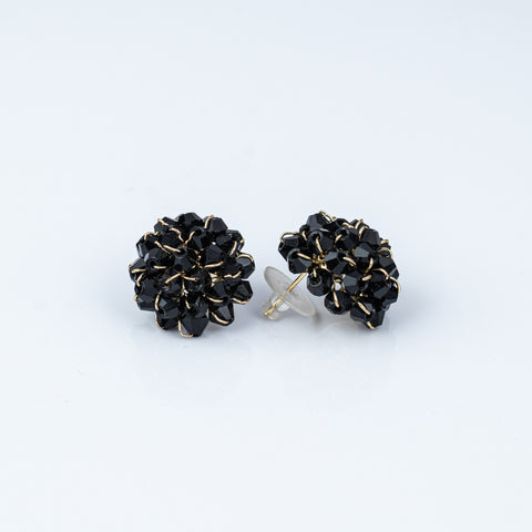 Pair of black floral earrings with gold accents on a white background