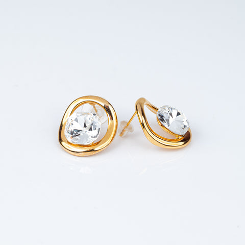 Gold earrings with clear gemstones on a light gray background