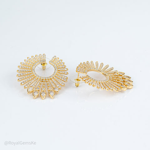 A pair of gold crescent-shaped hoop earrings adorned with clear pavé crystals and dangling teardrop crystal drops, displayed on a clean white background.