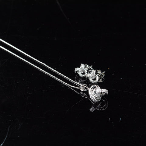 Silver snake pendant necklace and matching stud earrings on a black reflective surface.