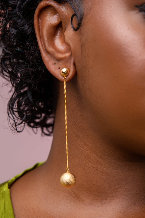 Gold earring worn by a person with a blurred background