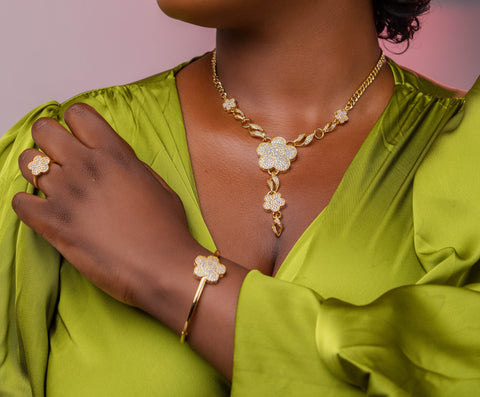Woman wearing a gold necklace, ring, and bracelet against a pink background