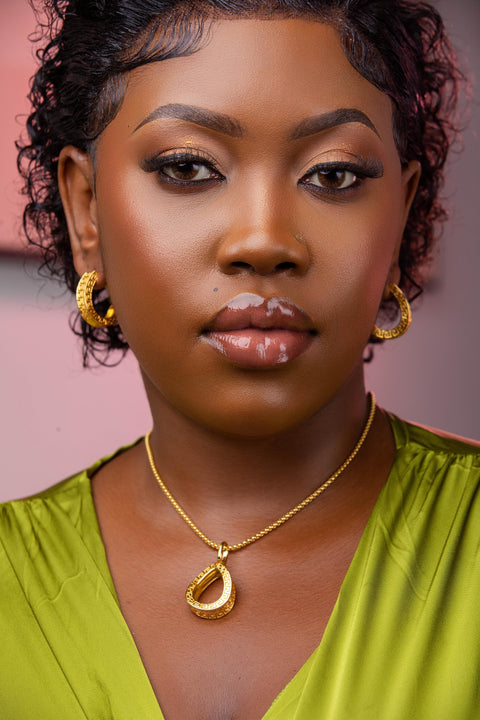 Woman wearing gold jewelry against a pink background