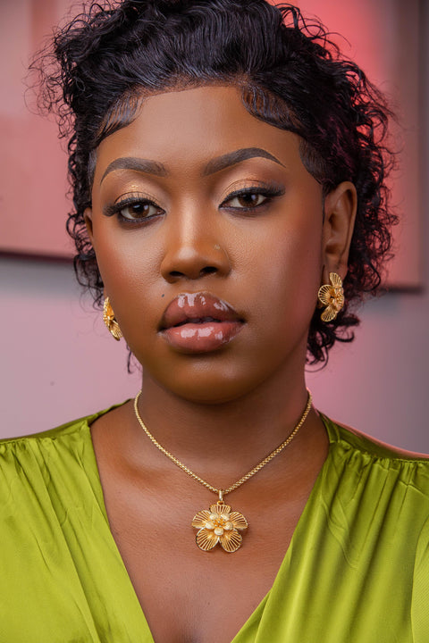 Woman wearing a green top and gold jewelry with a blurred background