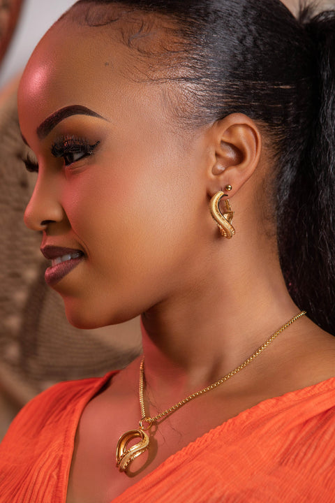 Woman wearing gold earrings and necklace with a blurred background