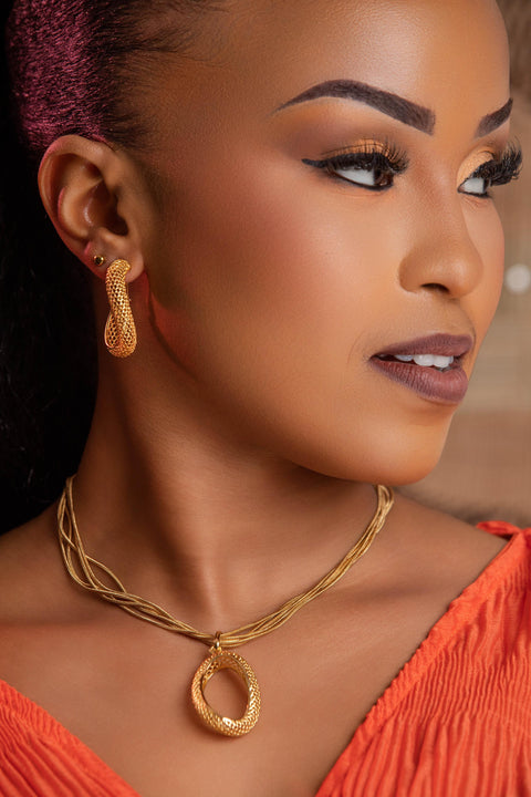 Woman wearing gold jewelry with an orange top against a blurred background