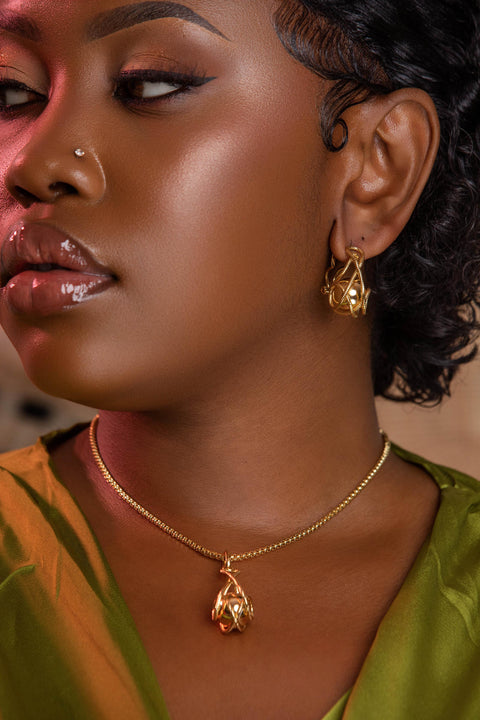 Woman wearing gold jewelry including earrings and a necklace.