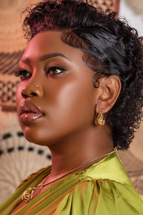 Woman with styled hair wearing a green top against a patterned background