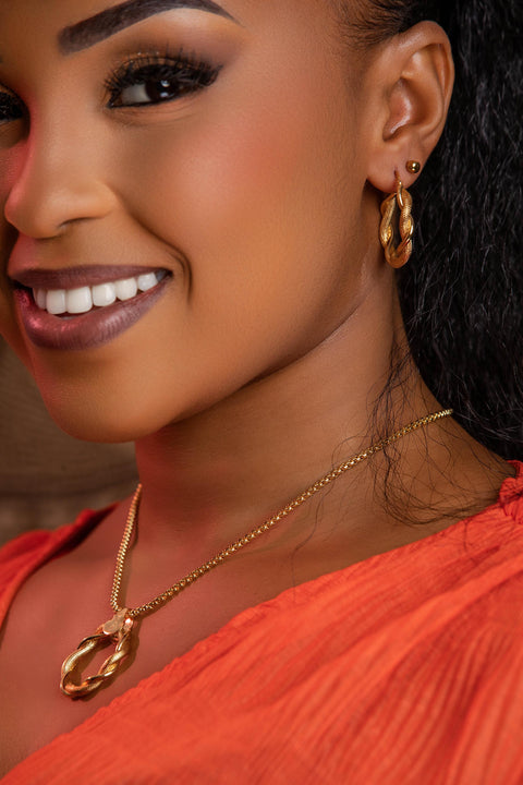 Close-up of a woman wearing gold jewelry including earrings and a necklace.