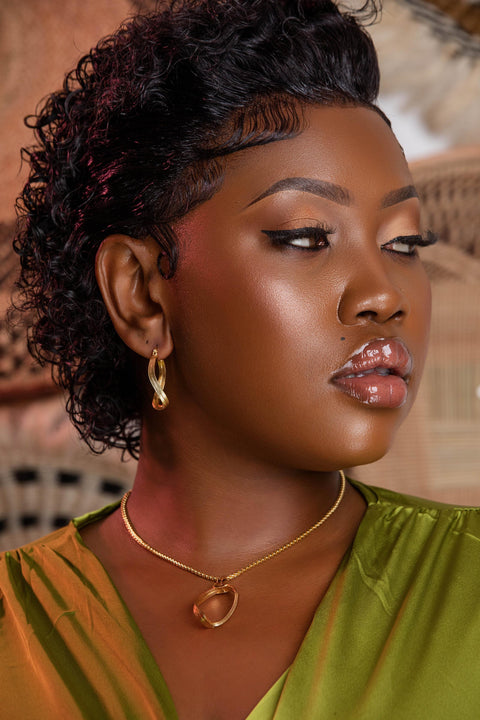 Woman with styled hair wearing a green top and gold jewelry