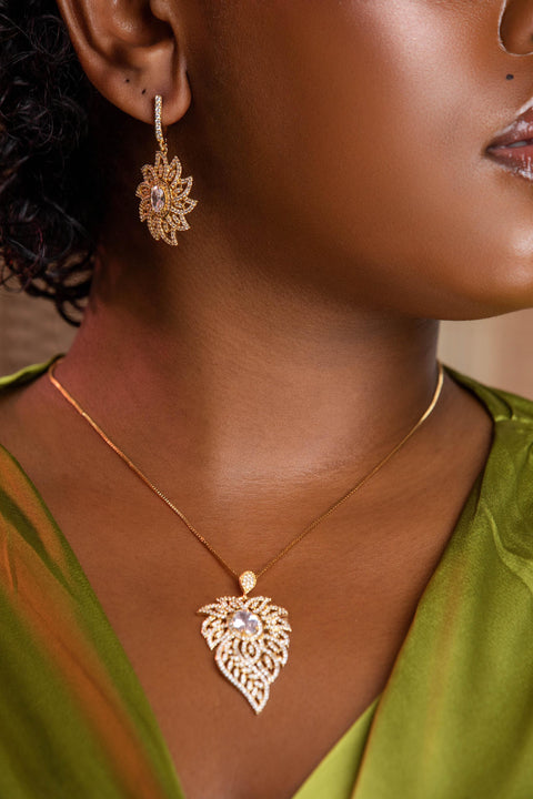 Close-up of a person wearing gold earrings and necklace against a neutral background