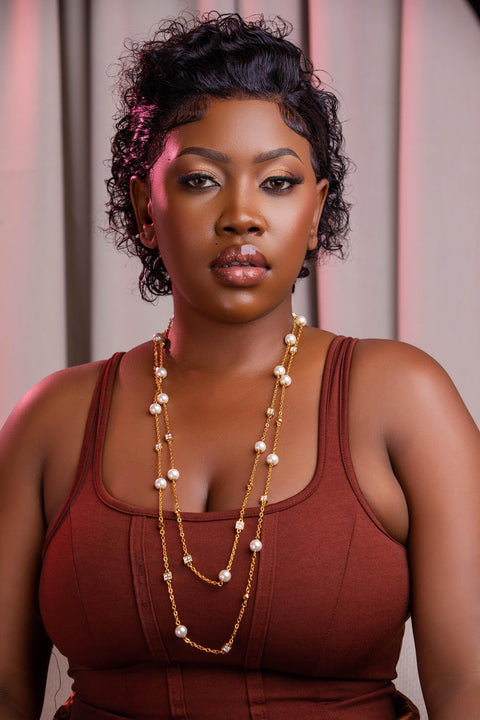 Woman wearing a red top and pearl necklace against a neutral background