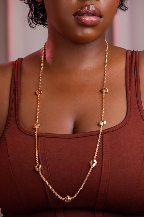 Woman wearing a gold necklace with a blurred background