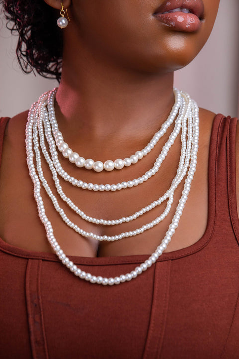 Woman wearing a multi-layered pearl necklace against a neutral background