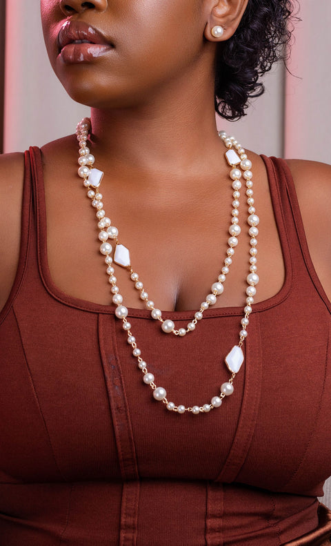 Woman wearing a long pearl necklace with a blurred background