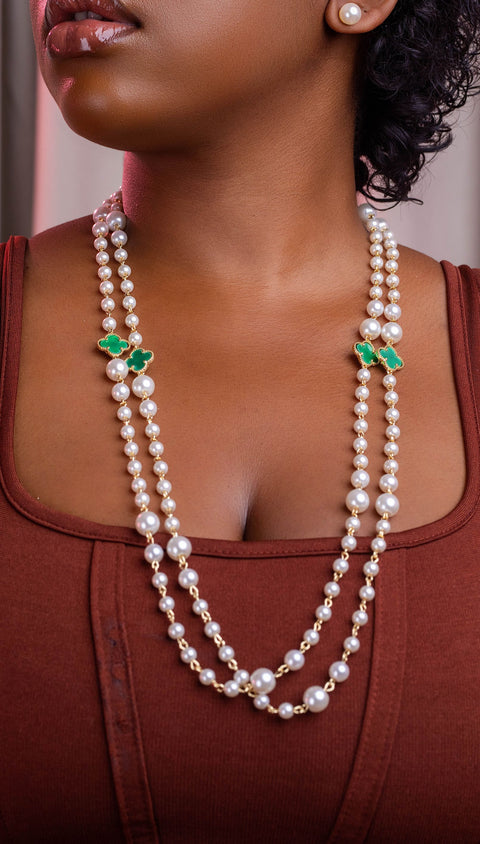 Woman wearing a pearl necklace with green accents