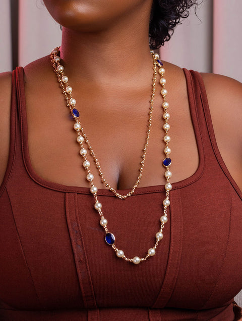 Person wearing a long pearl necklace with a blurred background