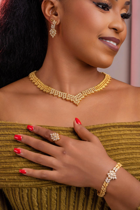 Woman wearing gold jewelry including a necklace, earrings, ring, and bracelet.