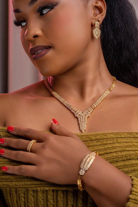 Woman wearing gold jewelry including a necklace, earrings, ring, and bracelet.