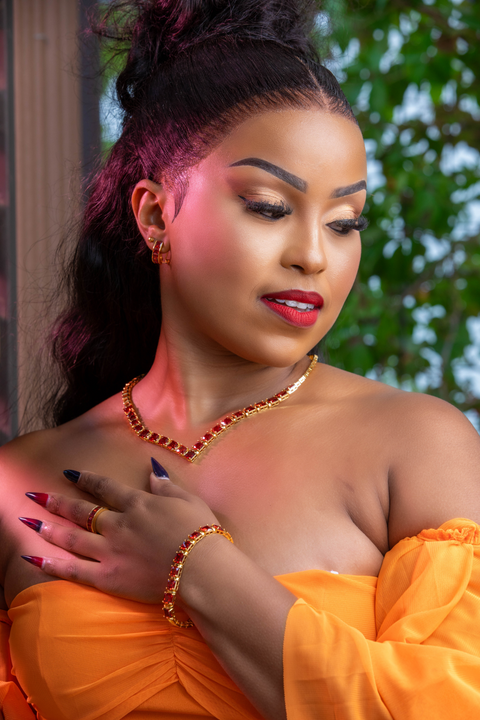 Woman wearing an orange outfit with jewelry against a blurred natural background