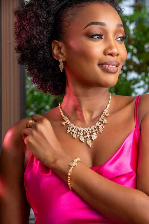 Woman wearing a pink top and gold jewelry with a blurred green background