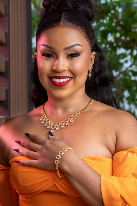 Woman in an orange dress with jewelry, smiling outdoors