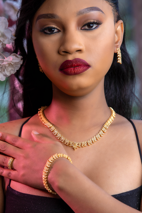 Woman wearing gold jewelry with a blurred floral background
