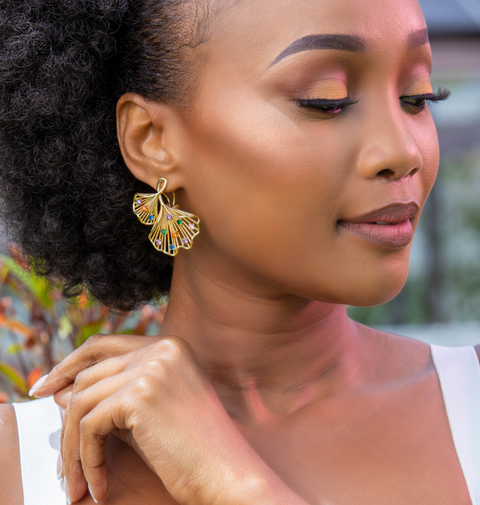 Woman wearing gold earrings and bracelet with a blurred background