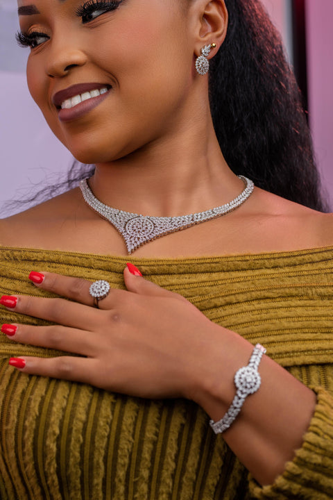 Woman wearing a diamond necklace, ring, and bracelet with a mustard yellow top.