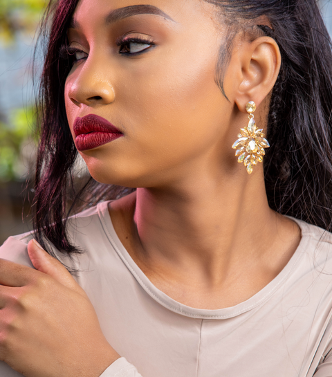 Woman wearing gold earrings and a bracelet with a blurred background