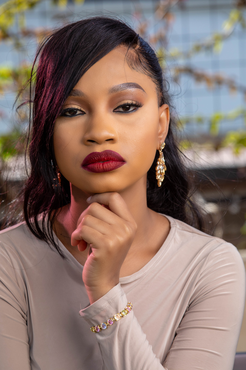 Woman with dark hair and red lipstick posing outdoors