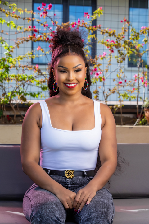 Woman sitting outdoors with flowers and a building in the background