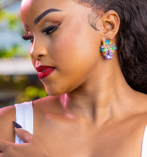Woman wearing colorful earrings and a gold bracelet with a blurred background
