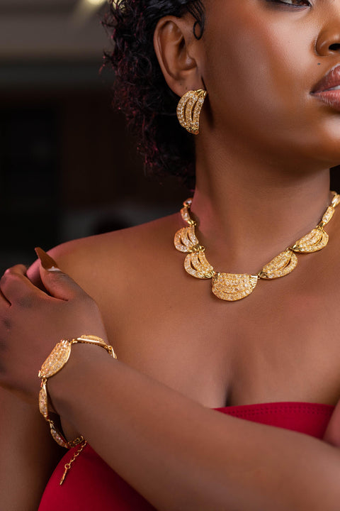 Woman wearing gold jewelry including a necklace, bracelet, and earrings.