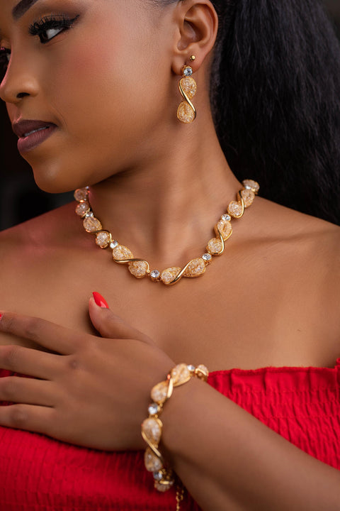 Woman wearing gold jewelry including a necklace, earrings, and bracelet.