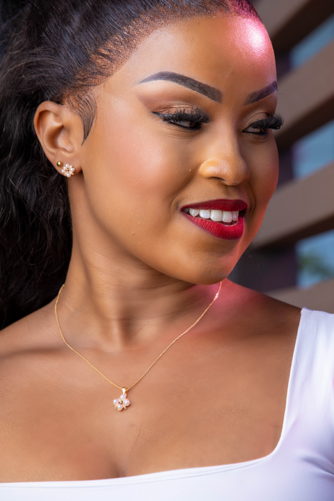 Woman wearing a gold necklace with a pendant, close-up of her neck and shoulders.