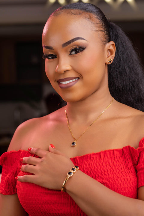 Woman wearing a red off-shoulder top with jewelry, posing indoors.