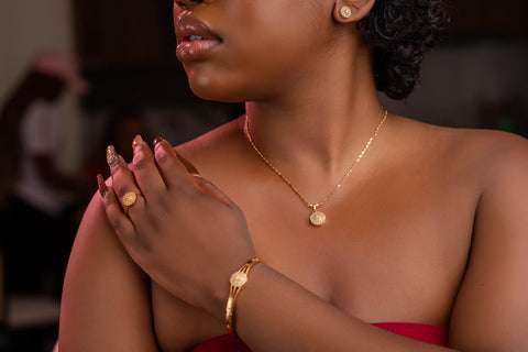 Woman wearing gold jewelry including a necklace, ring, and bracelet.