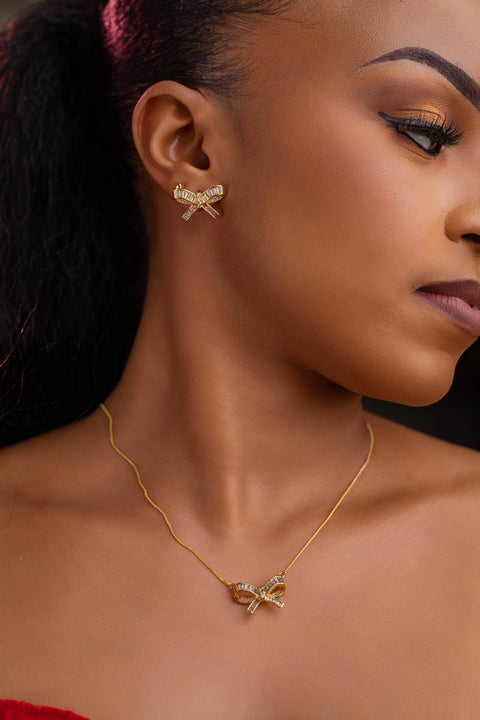 Close-up of a woman wearing gold earrings and necklace against a dark background