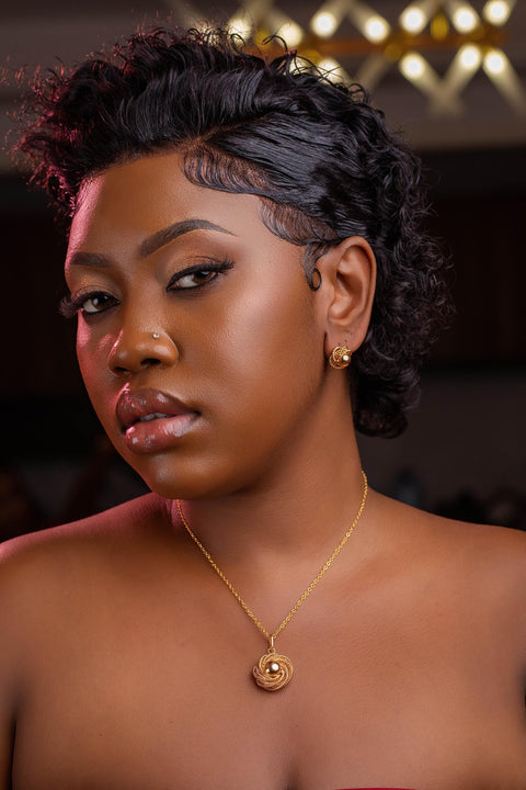 Woman wearing a gold necklace with a pendant against a blurred background