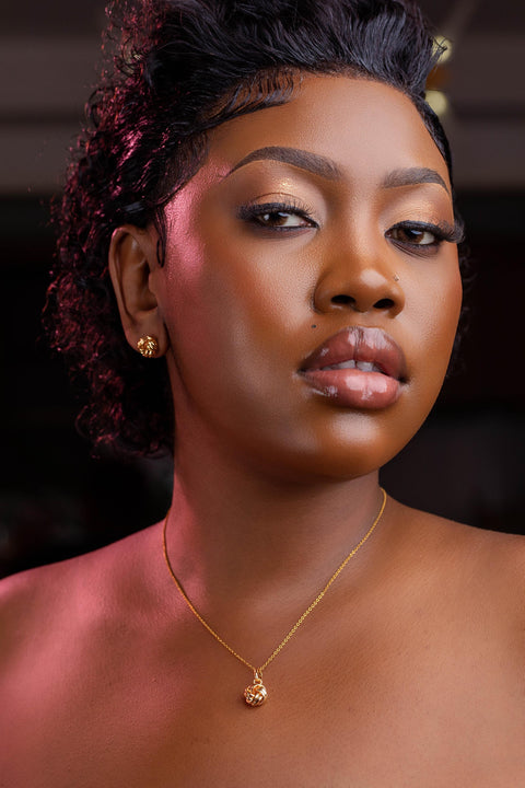 Woman wearing a gold necklace with a dark background