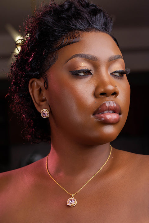 Woman wearing a gold necklace with a pendant, set against a blurred background