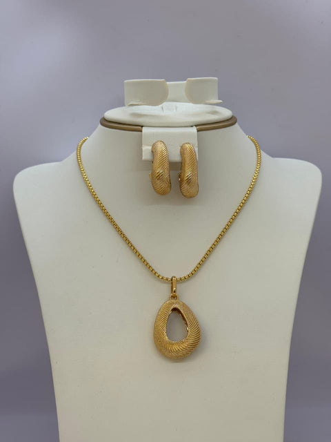 Gold necklace and earrings set on a mannequin bust against a gray background